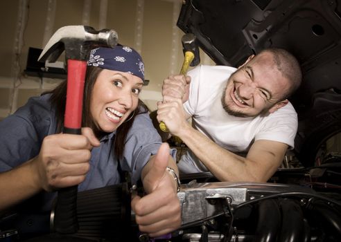 Hapless mechanics working on car engine with hammers