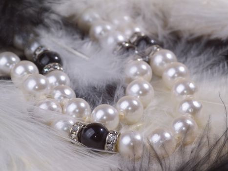 detail of pearl necklace on black and white feathers