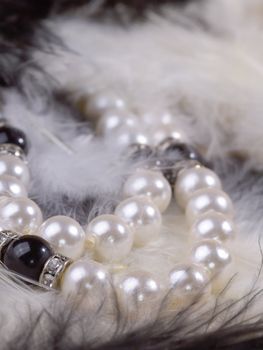detail of pearl necklace on black and white feathers