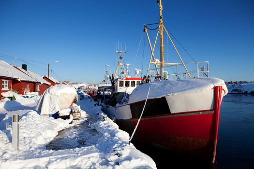 A dock in southern Norway with boats covered in snow