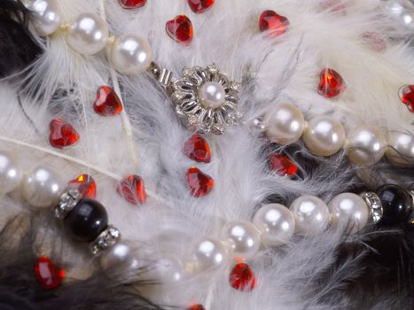 detail of pearl necklace on black and white feathers with strass hearts