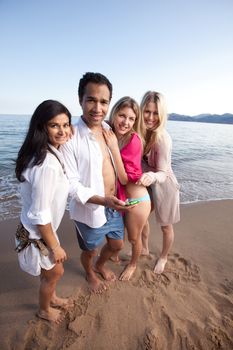 A group of friends looking at a cellphone at the beach