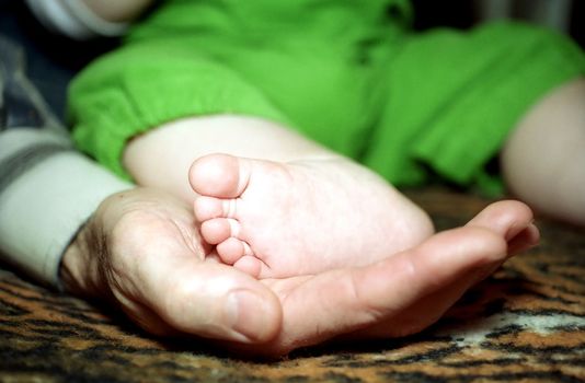 Infant foot on man's palm close up