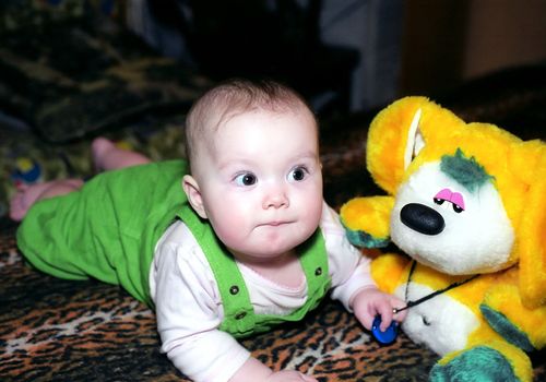 Infant with yellow chinchilla toy looks at something