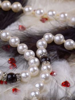 detail of pearl necklace on black and white feathers with strass hearts