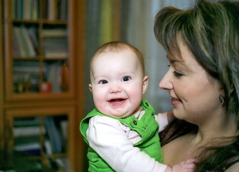 Laughing infant and mother looking at her with tender smile