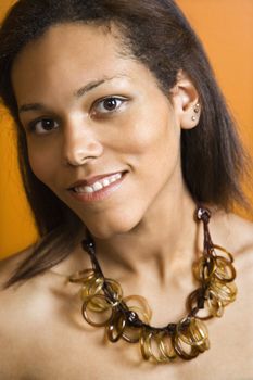 Attractive Africacn American woman smiling at viewer wearing large necklace.