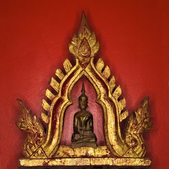 Golden Buddha statue against red wall.