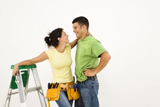 Couple with tools and ladder standing in home smiling.
