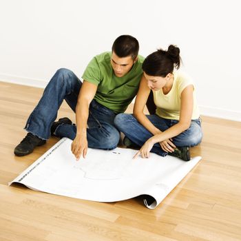 Attractive young adult couple looking at house plans.