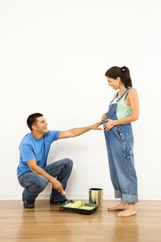 Pregnant woman and husband preparing to paint interior home wall.