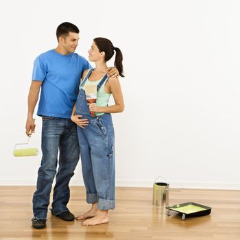 Pregnant woman and husband preparing to paint interior home wall.