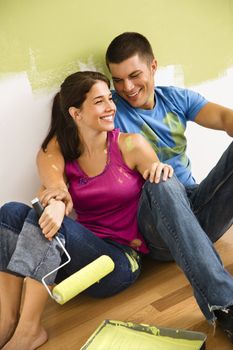 Couple sitting on floor smiling taking a break from painting home.