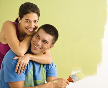 Happy smiling couple painting interior wall of home.