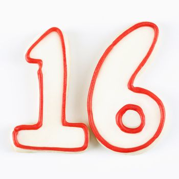 Sugar cookies in the shape of the number sixteen outlined in red icing.