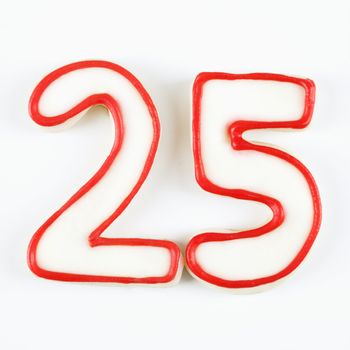 Sugar cookies in the shape of the number twenty five outlined in red icing.