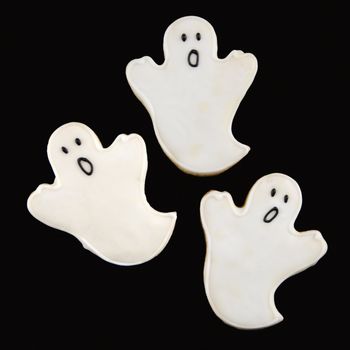 Three sugar cookies in shape of ghosts with decorative icing.