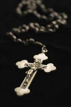 Christian rosary beads with crucifix on black background.