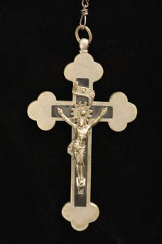 Close up of crucifix pendant against black background.