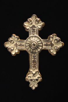 Ornamental religious cross against black background.