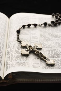 Rosary with crucifix lying on open Bible.