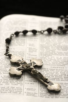 Rosary with crucifix lying on open Bible.