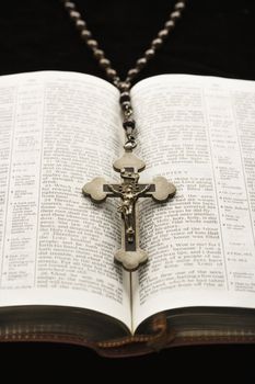 Rosary with crucifix lying on open Bible.