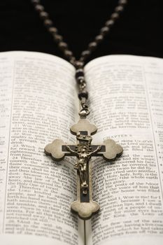 Rosary with crucifix lying on open Bible.