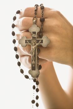 Woman's hands holding rosary with crucifix.