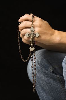 Woman's hands holding rosary with crucifix.