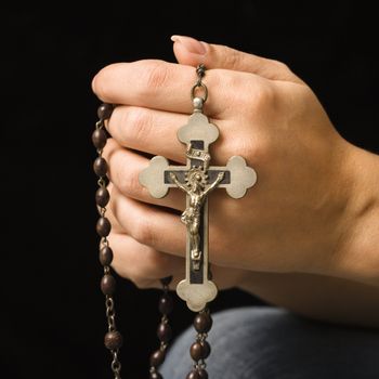 Woman's hands holding rosary with crucifix.