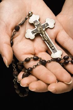 Woman's hands palm up cradling rosary with crucifix.