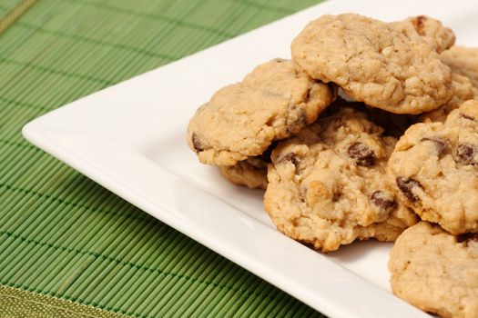A plate of oatmeal chocolate chip cookies on a green mat
