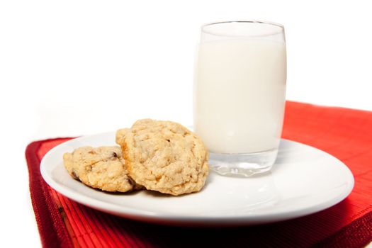 A plate of chocolate chip cookies and a tall glass of milk