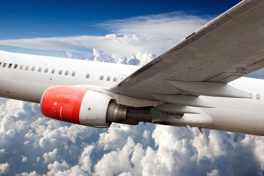 A large commercial passenger airplane in flight over clouds