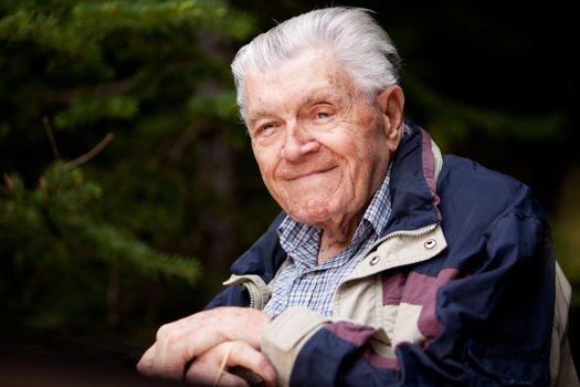 A portrait of an elderly man resting in the forest.