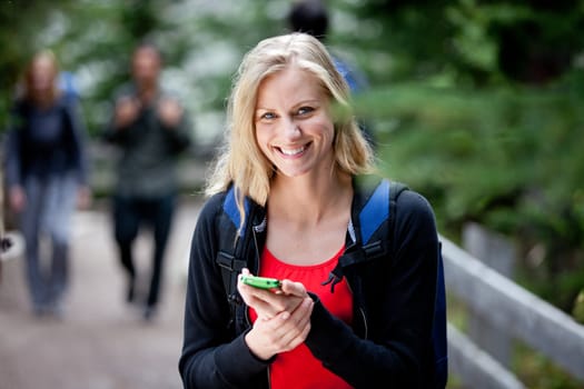 A happy woman holding a smart phone, looking at the camera