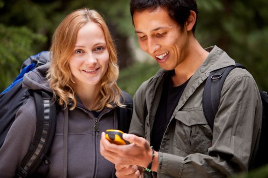 A man and woman looking at a gps in the forest