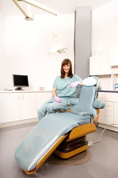 A dental hygienist sitting at a dental chair in a clinic