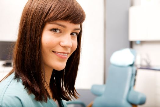 A portrait of a dental hygienist in front of a dental chair