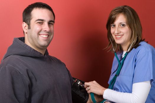 A young nurse checks the blood pressure of her patient.