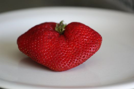 Close up of a strawberry on a plate.
