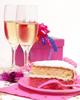 A slice of cake in front of two glasses of champagne.