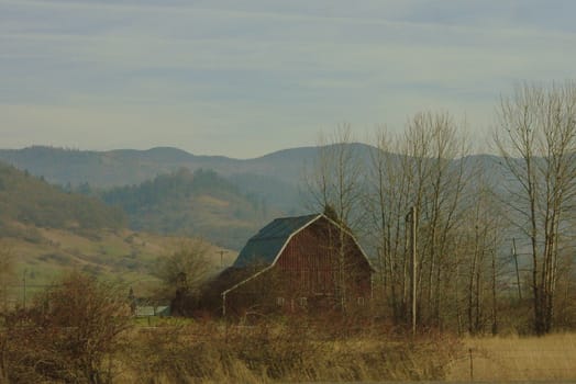 Red barn with mountains in background, Oregon, color, horizontal, grained image intentional