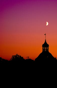 The moon on a dramatic sky over a old house.