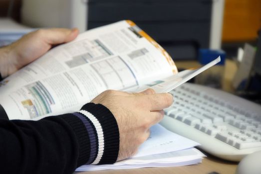 man sitting at the desk in office with magazine in hands