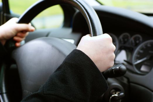 Two hands on a wheel, in the background the car interior.