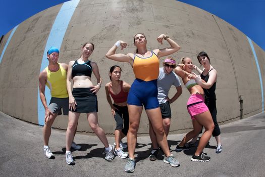 Pretty female runner poses and flexes with friends