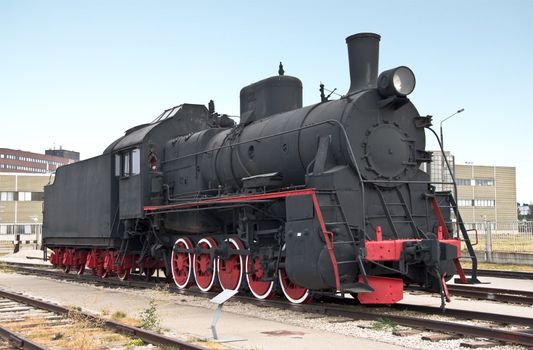 Steam locomotive beside a railway station platform. Retro train.