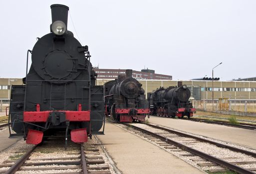 Steam locomotives beside a railway station platform. Retro train.